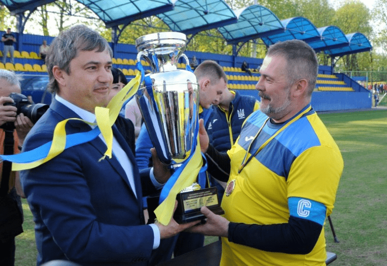 Перший віцепрезидент ФФУ Вадим Костюченко вручає кубок гравцю збірної народних депутатів Юрію Березі після благодійного футбольного матчу "Парламентський кубок-2018" / УНІАН