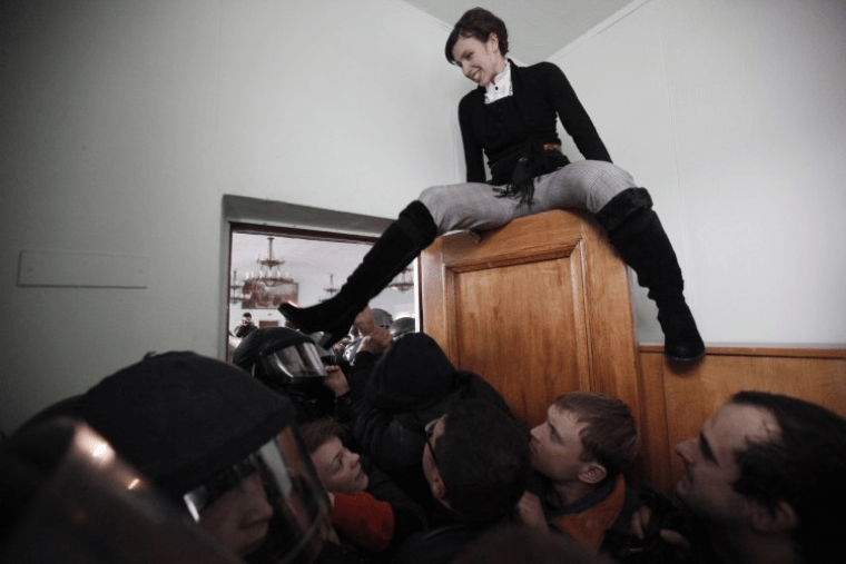 Журналістка Тетяна Чорновол сидить на дверях під час бійки між активістами ВО "Свобода" і міліцією/Головпоштамт, Києв, 2013 р. / УНІАН