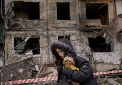 Женщина с собакой на фоне разрушенного российскими оккупантами дома, Украина