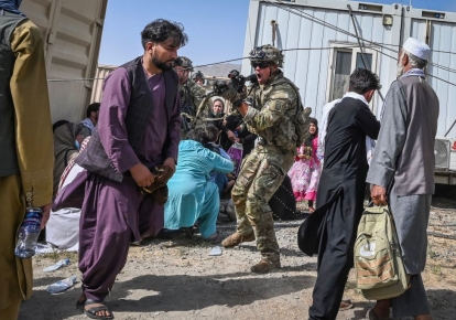 Солдат США направляет оружие в сторону афганского пассажира в кабульском аэропорту 16 августа 2021