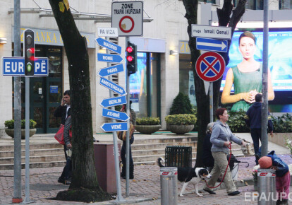 Жінка гулеят з собакою біля символічних дорожніх знаків, провідних до європейських містах у центрі Тирани, Албанія, 2010 р. EPA/UPG