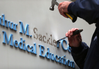 Рабочий убирает буквы фамилии Саклер с вывески в здании Университета Тафтса в Бостоне / Getty Images