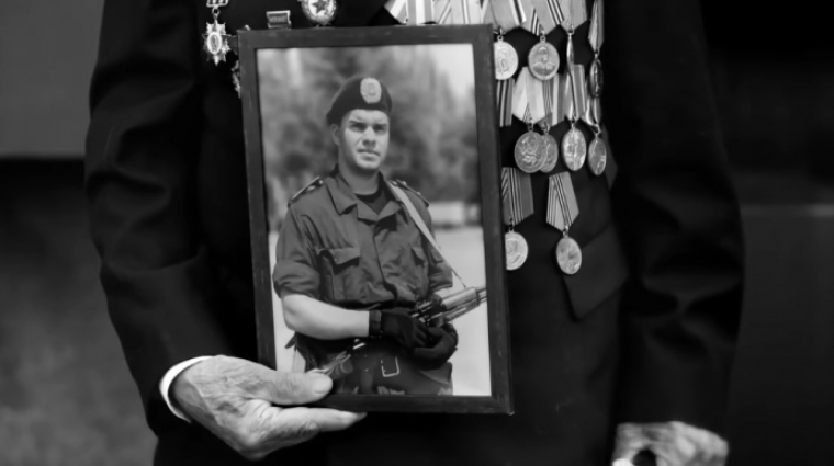 Иван Залужный держит фото своего внука Ивана Гутника-Залужного, погибшего в бою с российскими оккупантами